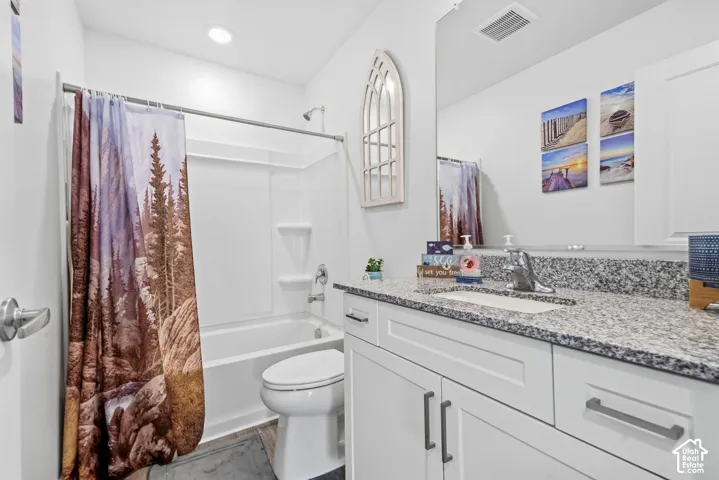 White vanity with shaker-style cabinetry, granite countertop, undermount sink, and polished chrome faucet