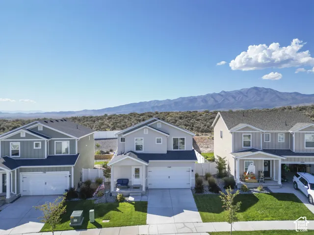 Two-story stucco and siding residence with an attached two-car garage, covered porch, and manicured front lawn