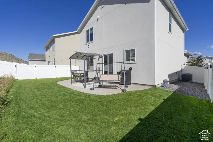 Expansive backyard featuring a manicured lawn, white privacy fencing, and a concrete patio