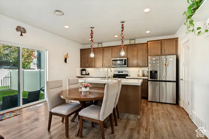 Open-concept kitchen and dining area featuring wood-finish flooring, recessed lighting, and a sliding glass door to the exterior