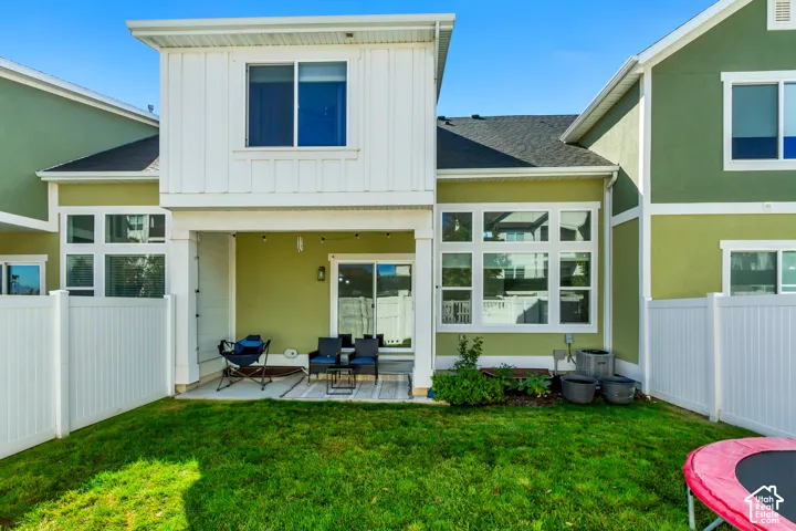 Exterior featuring a covered patio, sliding glass door, multiple large windows, and a fenced yard
