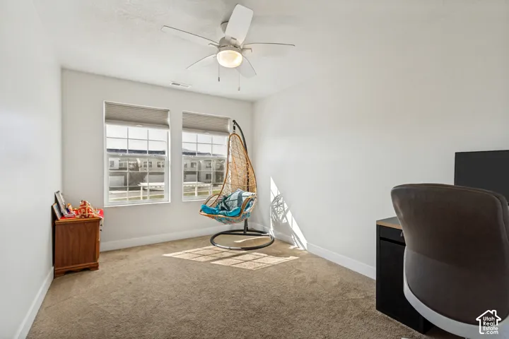 Neutral wall paint with carpeted flooring, complemented by a ceiling fan with integrated lighting