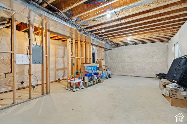 Unfinished basement offering exposed wood framing, concrete flooring, visible ductwork, and overhead lighting