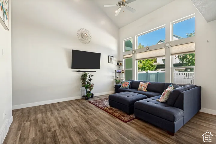 Vaulted ceiling with a ceiling fan, wood-finish flooring, and expansive windows