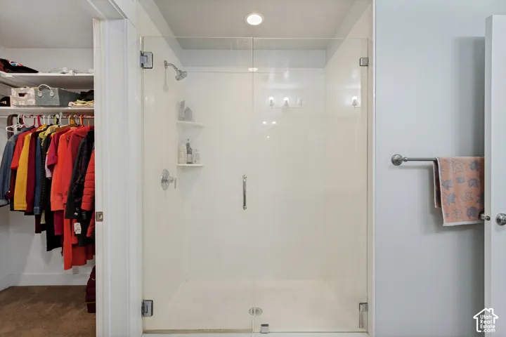 Frameless glass shower enclosure featuring a chrome showerhead and built-in shelving