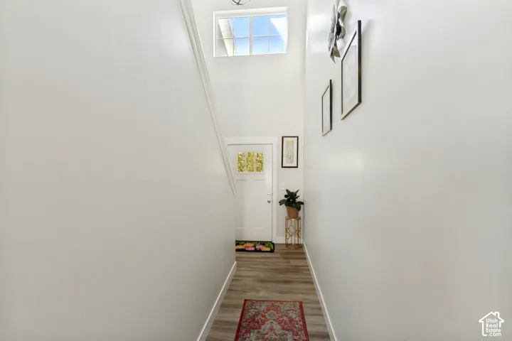 Two-story entry with wood-finish flooring, white walls, and a transom window