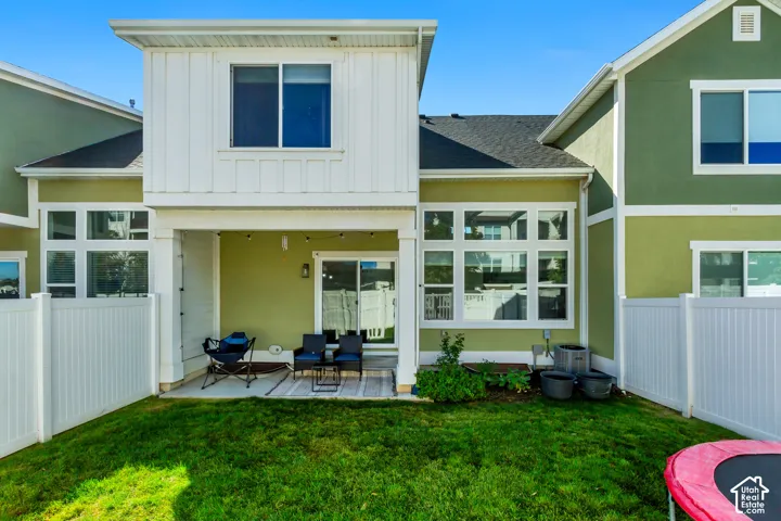 Private fenced backyard with a covered patio, sliding glass door, and green exterior siding