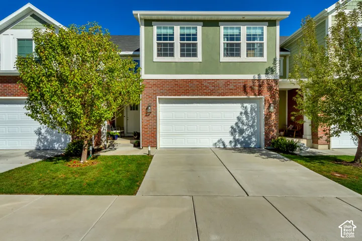 Brick and siding exterior featuring a two-car garage, multiple windows with grid patterns, and a covered entry