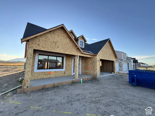 New construction with black shingle roofing, integrated garage, and a concrete porch