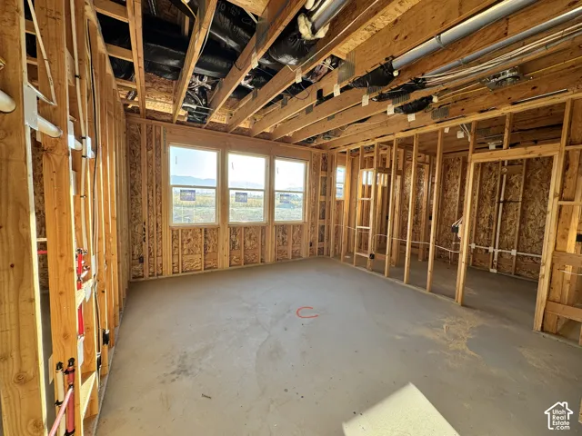 Framed interior space with exposed ceiling joists, concrete flooring, and multiple windows