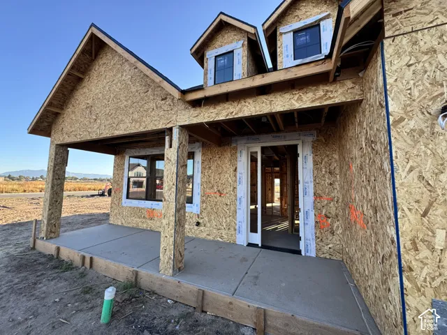 Front porch with a concrete slab, exposed structural wood framing, and multiple window openings