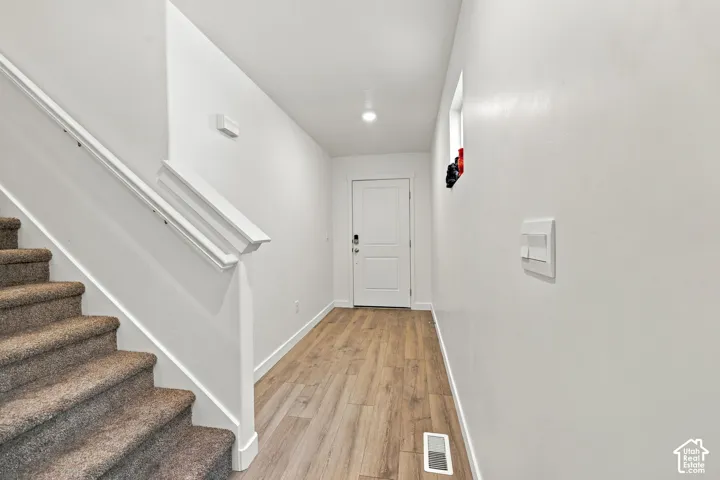 Wood-finish flooring, white walls, and a staircase with carpeted treads