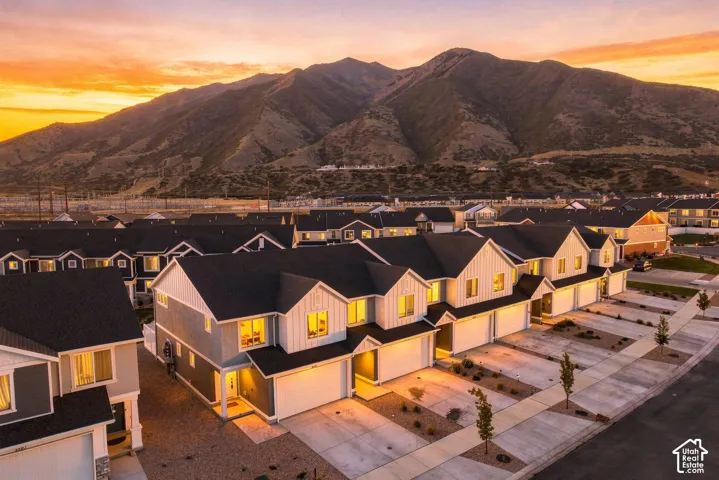 Modern townhome community with a mountain backdrop, featuring individual garages, multi-story facades, and contemporary landscaping