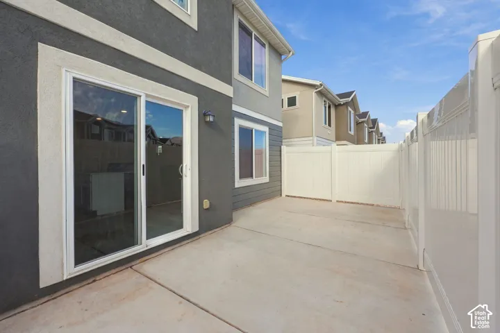 Concrete patio with a white vinyl fence and a sliding glass door