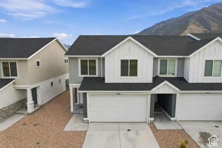 Multi-story townhome featuring a two-car garage, board and batten accents, and a mountain backdrop