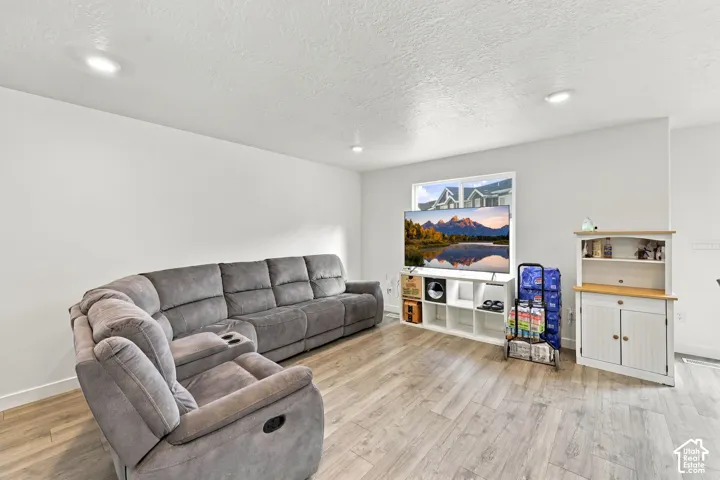 Finished Basement Recreation Room featuring plush reclining seating, wood-finish flooring throughout, recessed ceiling lighting, and built-in shelving and storage cabinetry