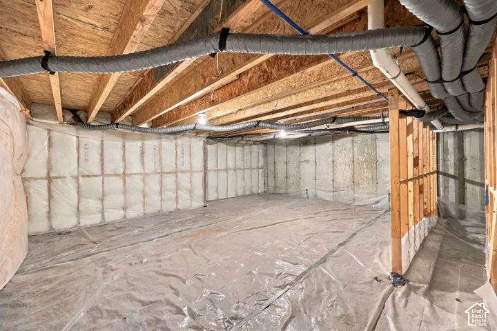 Unfinished lower level featuring exposed wood joists, concrete foundation walls, and insulation