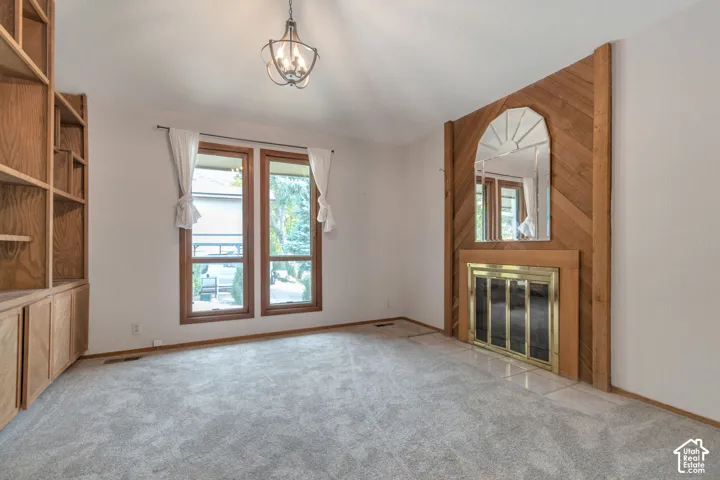 Built-in shelving, wood-framed windows, fireplace with wood-paneled surround, and overhead light fixture