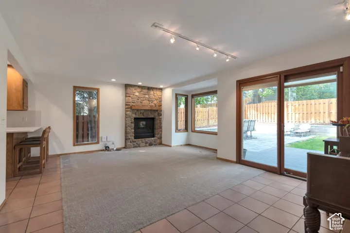 Stone-faced fireplace with a wood mantle, sliding glass patio doors, built-in breakfast bar, and multiple windows