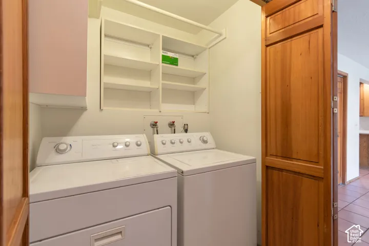 Laundry area featuring built-in shelving, white appliances, and a wood-panel door