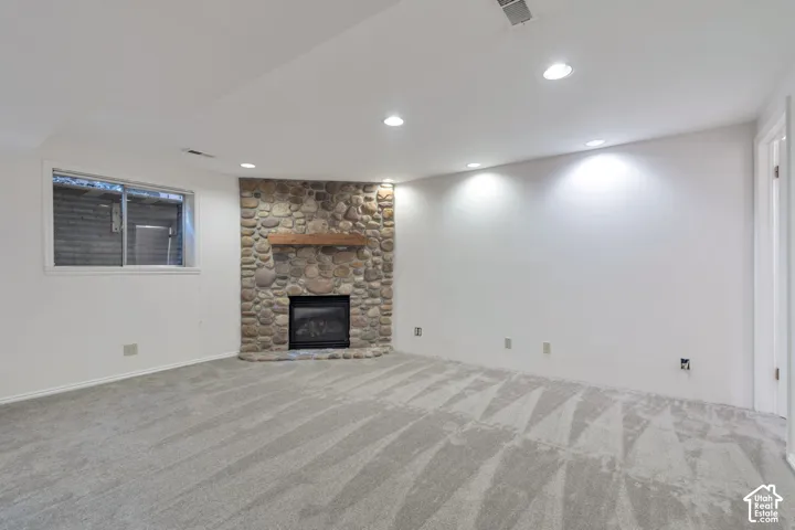 Recessed lighting illuminates the room, featuring a stone fireplace with a wood mantel