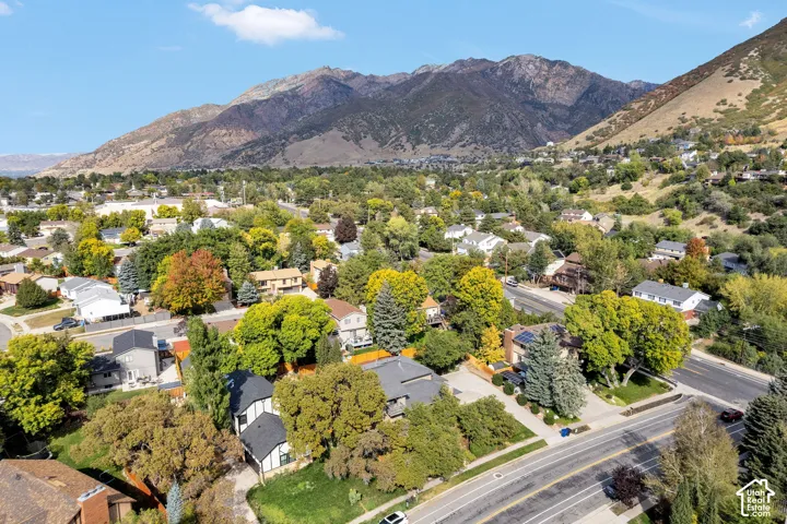 Residential neighborhood with mature trees, established homes, paved streets, and mountainous surroundings