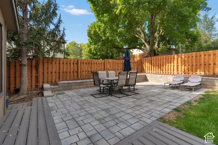 Expansive paver patio with a raised retaining wall, wood fencing, and a composite deck