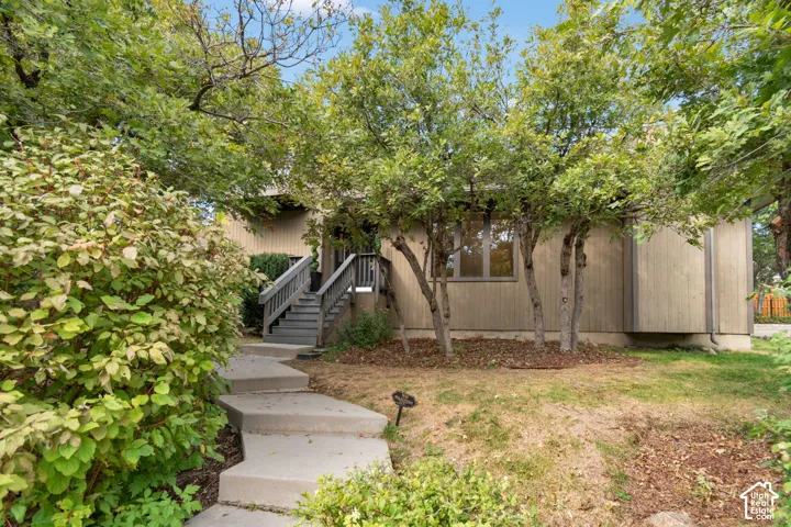 Mature landscaping with established trees and lush greenery frames this single-story residence