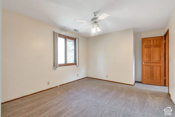 Neutral wall color, ceiling fan with integrated lighting, wood-framed window, and a paneled wood door