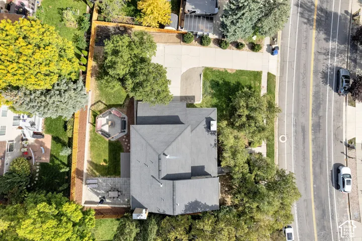 Expansive lot featuring a large driveway, established trees, a paved patio, and a fenced backyard with a gazebo