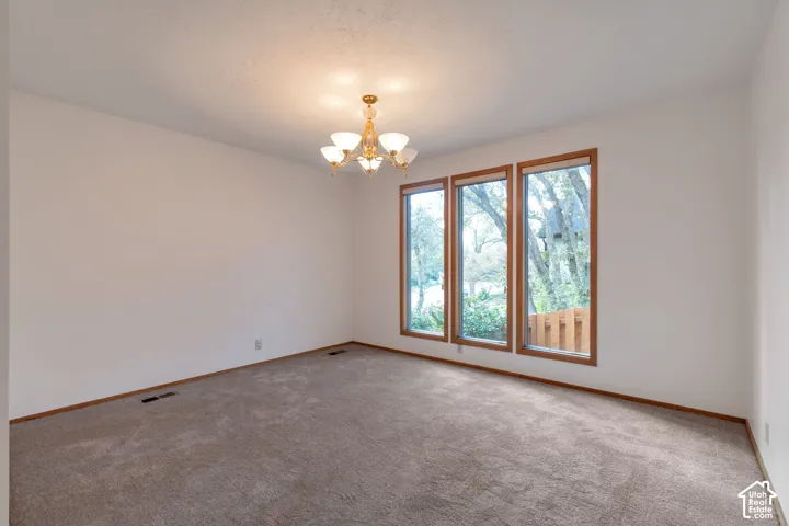Spacious room flooded with natural light through triple glass doors with wood frames, offering expansive windows overlooking mature landscaping