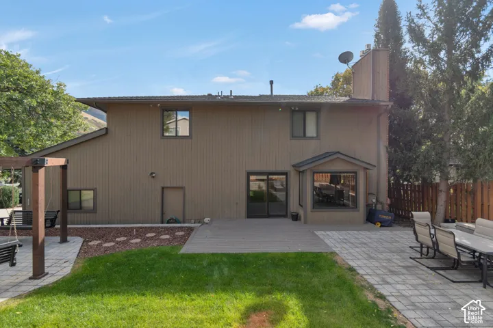 Expansive backyard featuring a manicured lawn, a large patio with paver stones, a composite deck, and a wooden privacy fence