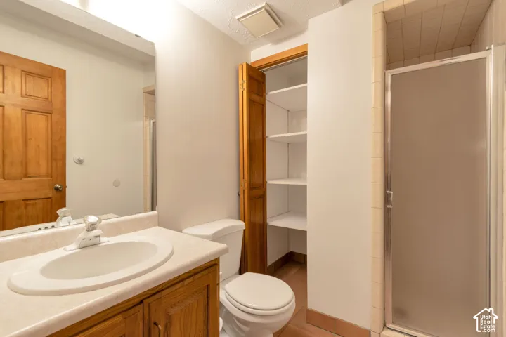 Bathroom featuring a wood-finish vanity with an undermount sink, laminate countertop, and large mirror with integrated lighting