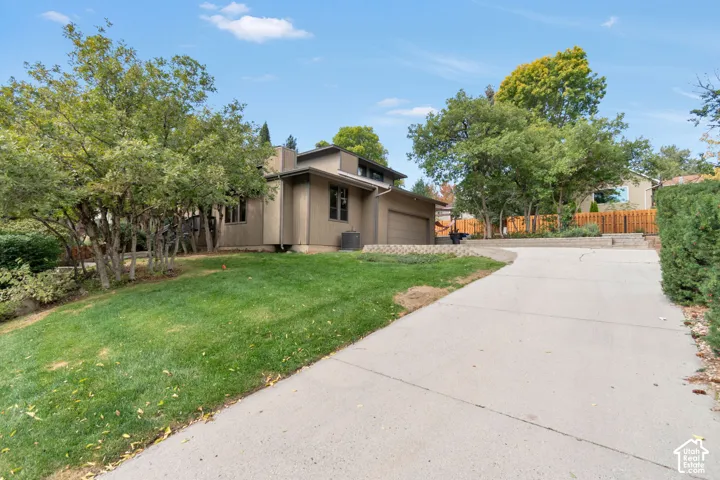 Concrete driveway leading to a multi-level home with an attached garage