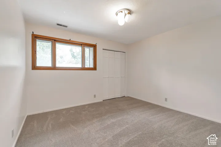 Neutral wall tones, carpet flooring, wooden window frame, and bi-fold closet doors