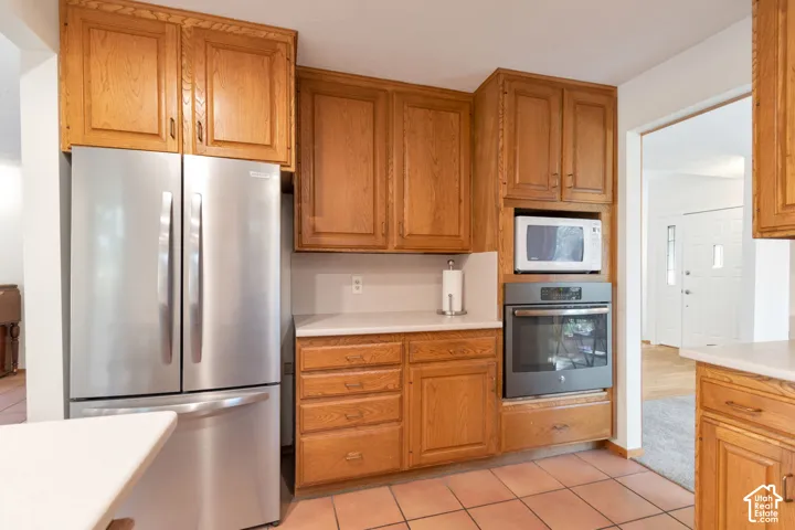 Warm wood cabinetry throughout this kitchen features stainless steel French-door refrigerator, built-in double wall oven, and quartz countertops