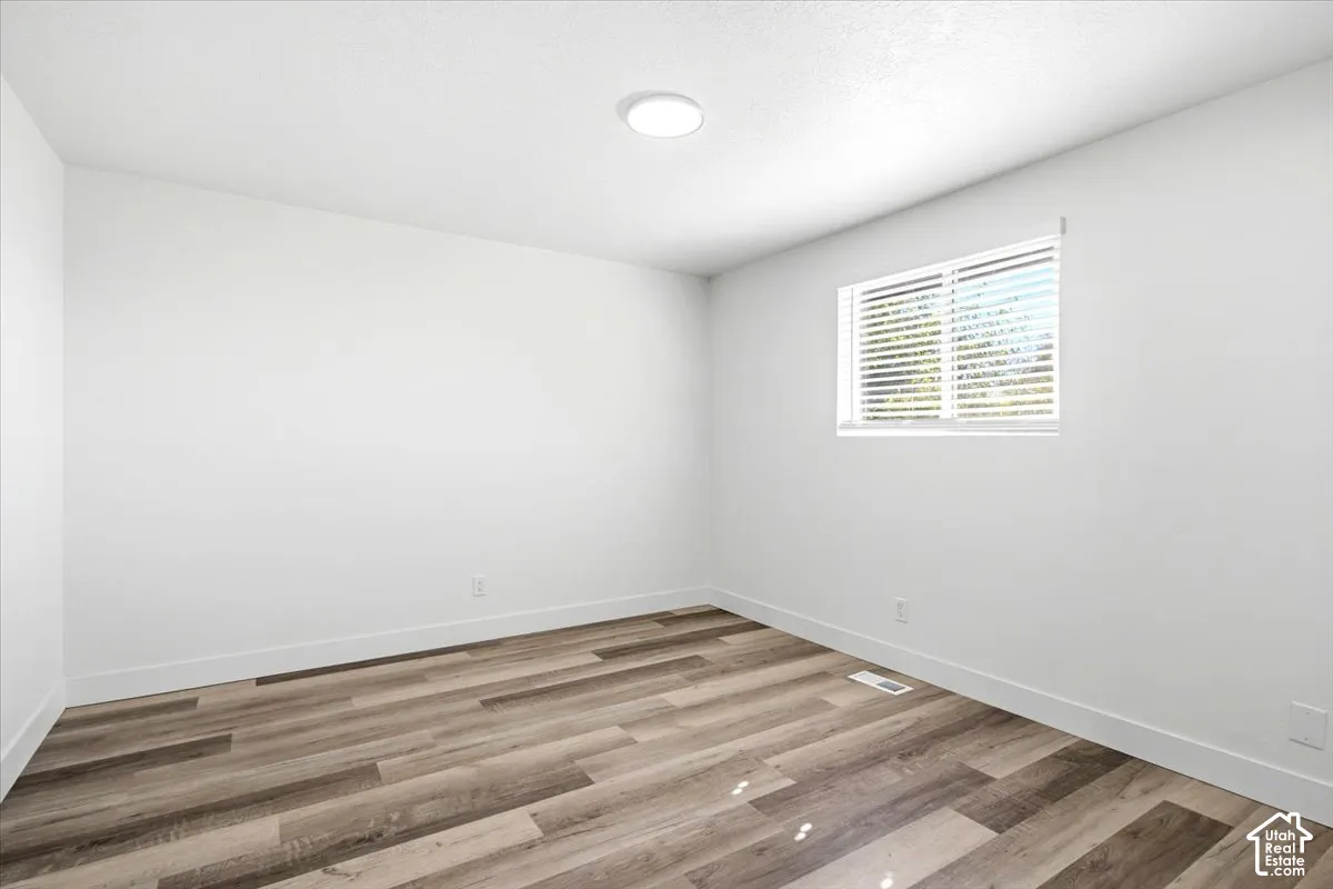 Bright interior space featuring wood-finish flooring, a window with blinds, and recessed lighting