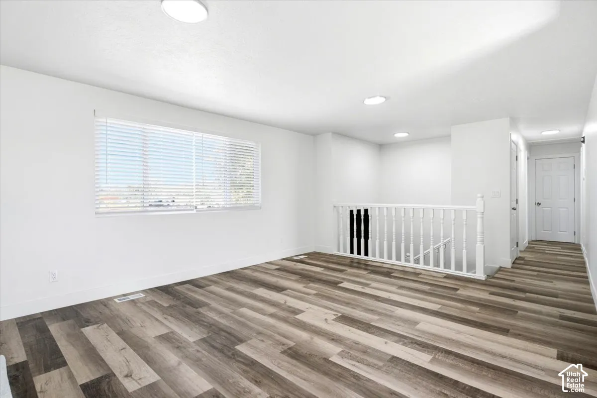 Expansive room featuring wood-finish flooring, recessed lighting, and a wide window with blinds