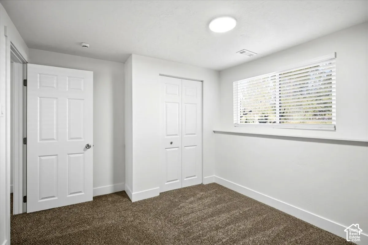 Neutral wall paint, plush carpet, window with blinds, bi-fold closet doors, and recessed lighting