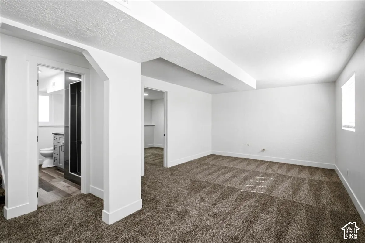 Neutral-toned carpeting, white walls, and a window with blinds