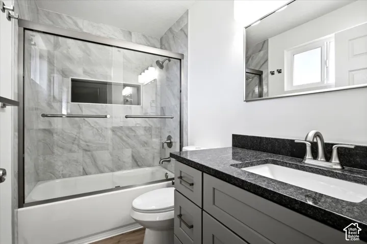 Bathtub with clear glass sliding shower doors and tiled surround, complete with a built-in shower niche