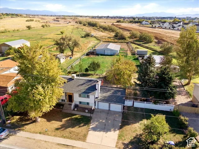 Split-level residence featuring a two-car garage, concrete driveway, and mature landscaping