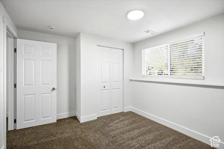 Neutral wall paint, plush carpet, window with blinds, bi-fold closet doors, and recessed lighting