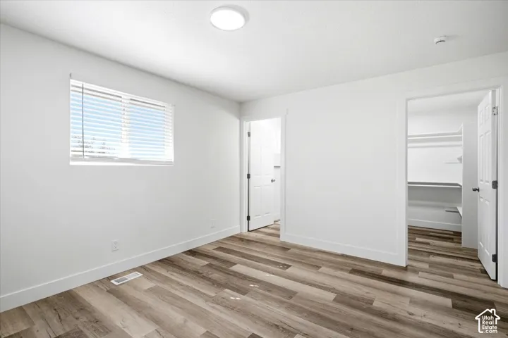 Neutral wall tones, wood-finish flooring, recessed ceiling lighting, and a walk-in closet with shelving