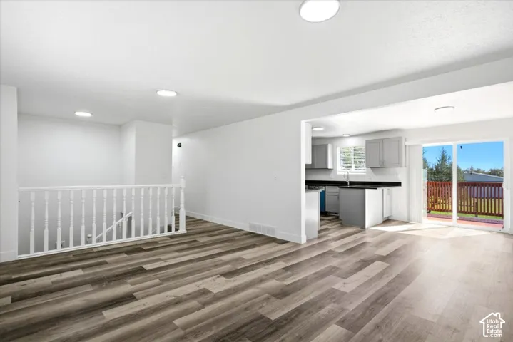 Open-concept living area with wood-finish flooring, recessed lighting, and a white baluster staircase
