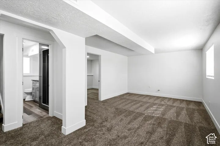Neutral-toned carpeting, white walls, and a window with blinds