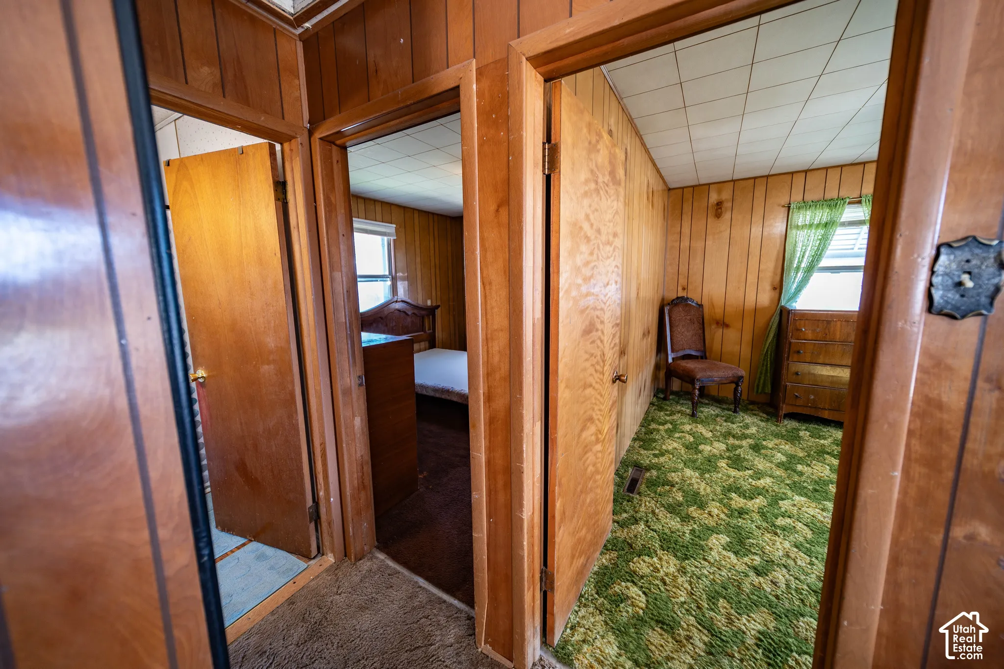 Wood paneling throughout, multiple doorways, and ceiling tiles