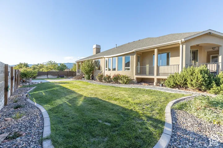 Expansive backyard with a manicured lawn, curved concrete curbing, and decorative rock landscaping