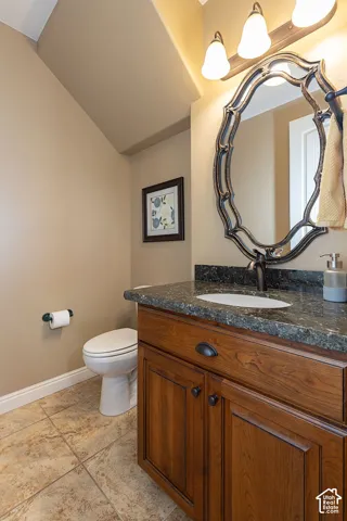 Wood-finish vanity with a built-in sink, dark countertop, and decorative framed mirror