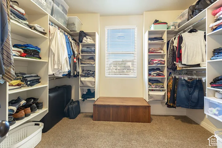 Walk-in closet featuring built-in shelving, hanging rods, and a central window with blinds